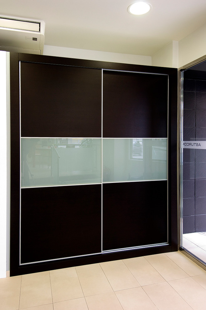 Cette image montre un petit placard dressing traditionnel neutre avec un placard à porte plane et des portes de placard noires.