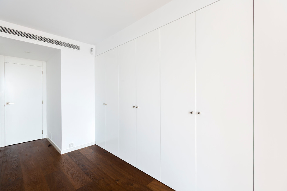 Modelo de armario unisex tradicional renovado de tamaño medio con armarios con paneles lisos, puertas de armario blancas y suelo de madera oscura