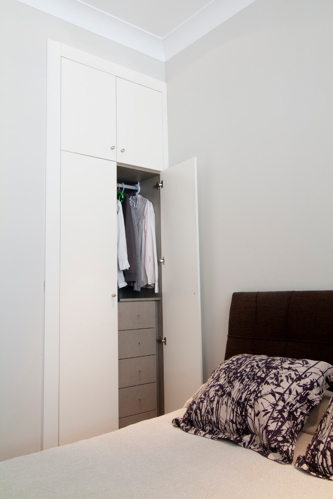 Ejemplo de armario unisex tradicional renovado pequeño con armarios con paneles lisos y puertas de armario blancas