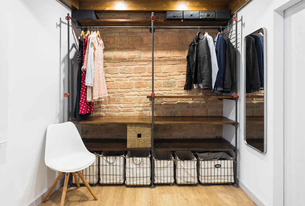 Inspiration för små industriella walk-in-closets för könsneutrala, med öppna hyllor, skåp i mörkt trä och ljust trägolv