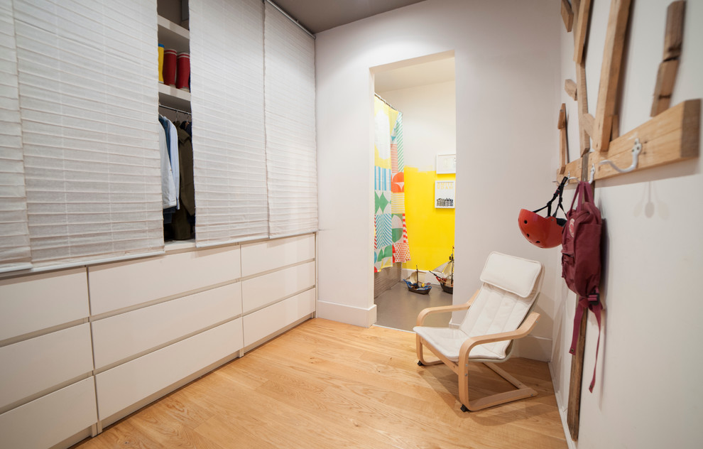 Idée de décoration pour un dressing room méditerranéen de taille moyenne et neutre avec un placard à porte plane, des portes de placard blanches et un sol en bois brun.