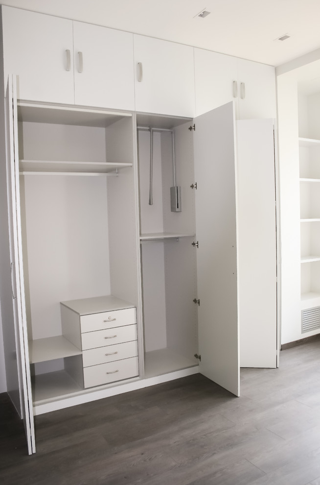 Foto de armario unisex tradicional renovado de tamaño medio con armarios con paneles lisos, puertas de armario blancas y suelo de madera oscura