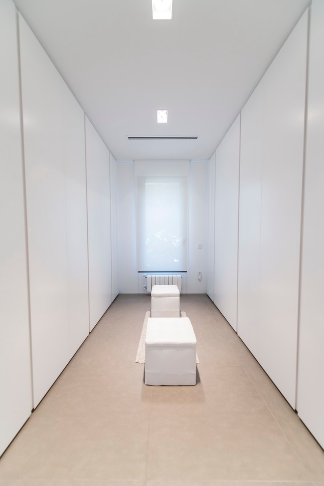 На фото: большая гардеробная комната унисекс в современном стиле с плоскими фасадами и белыми фасадами