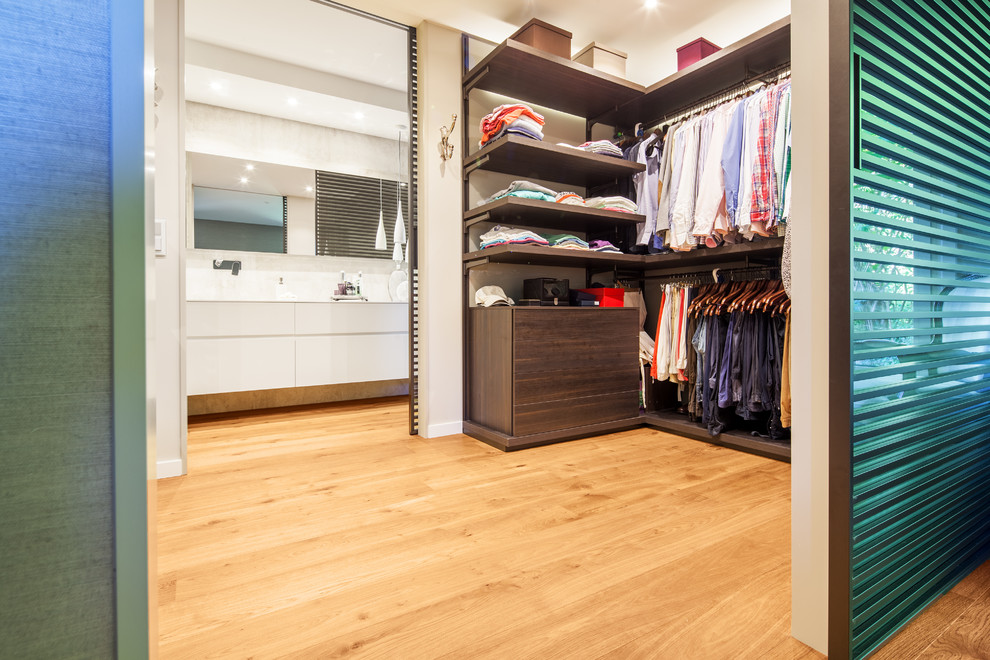 Cette photo montre un grand dressing room tendance en bois foncé neutre avec un placard sans porte et un sol en bois brun.