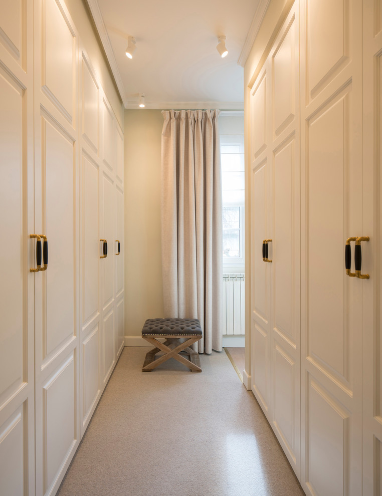 Cette photo montre un grand dressing room chic neutre avec un placard avec porte à panneau surélevé, des portes de placard blanches, moquette et un sol beige.