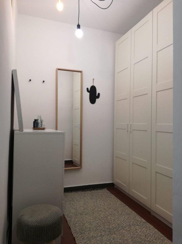 Exemple d'un petit dressing room neutre avec un placard avec porte à panneau surélevé, des portes de placard blanches et un sol rouge.