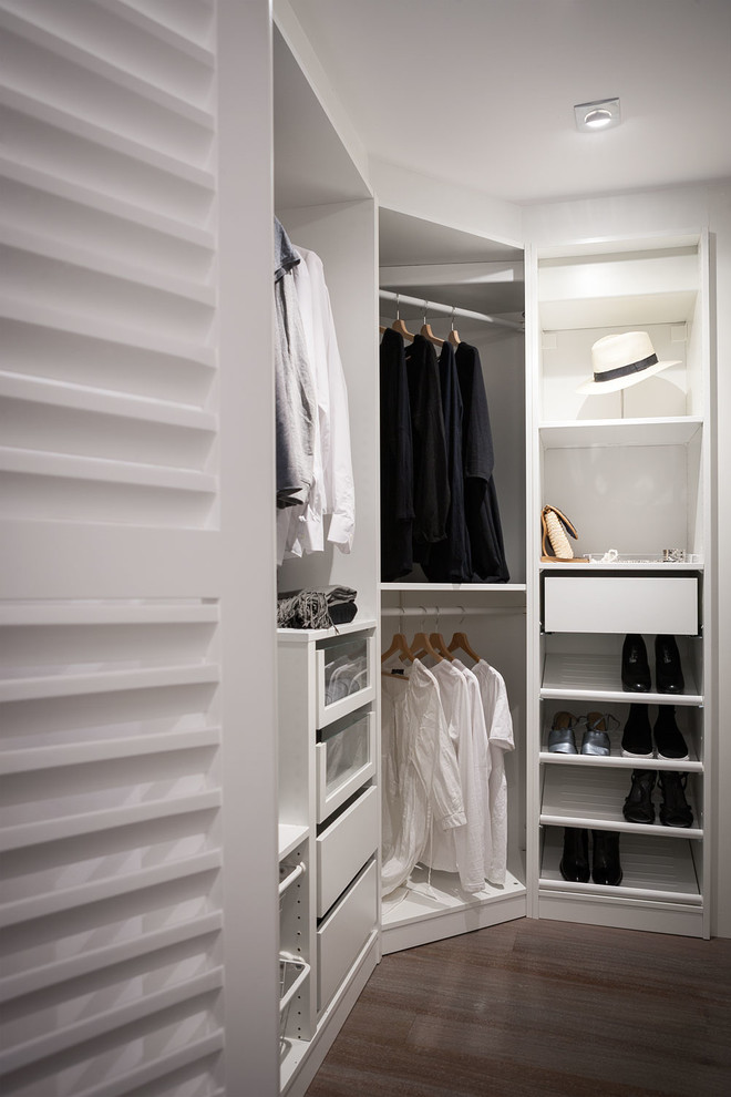 Diseño de armario vestidor unisex actual de tamaño medio con armarios abiertos, puertas de armario blancas y suelo de madera en tonos medios