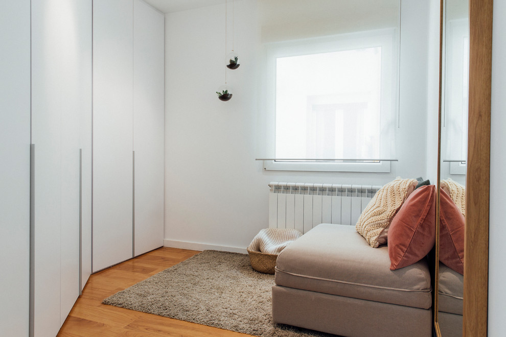 Foto di un armadio o armadio a muro per donna nordico di medie dimensioni con ante lisce, ante bianche, pavimento in legno massello medio e pavimento marrone
