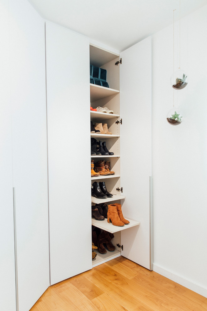 Foto de armario de mujer nórdico de tamaño medio con armarios con paneles lisos, puertas de armario blancas, suelo de madera en tonos medios y suelo marrón