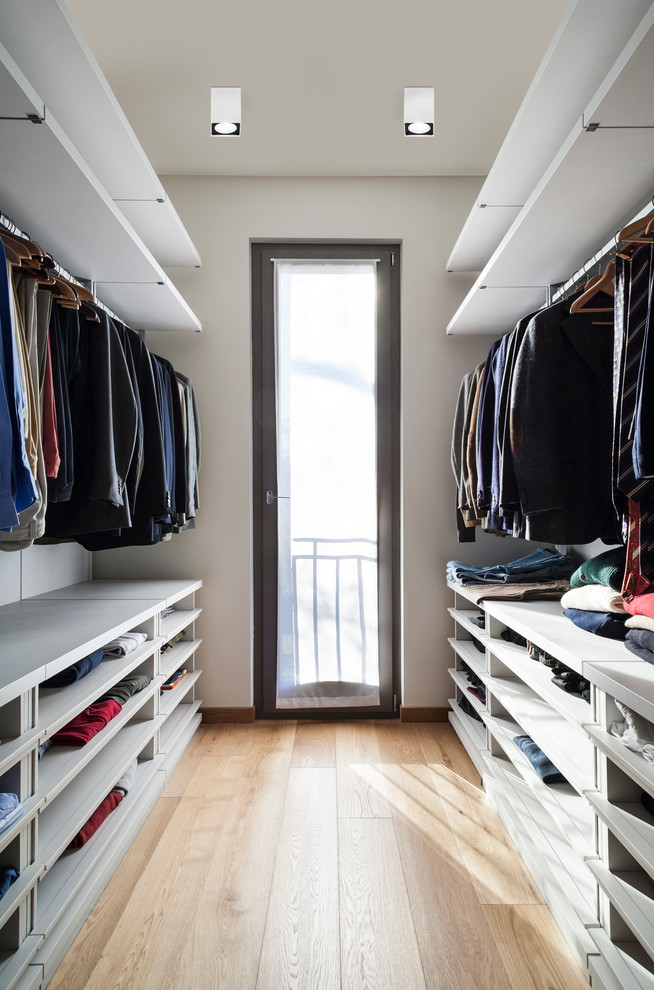 Foto de armario vestidor unisex minimalista de tamaño medio con armarios abiertos, puertas de armario blancas y suelo de madera en tonos medios