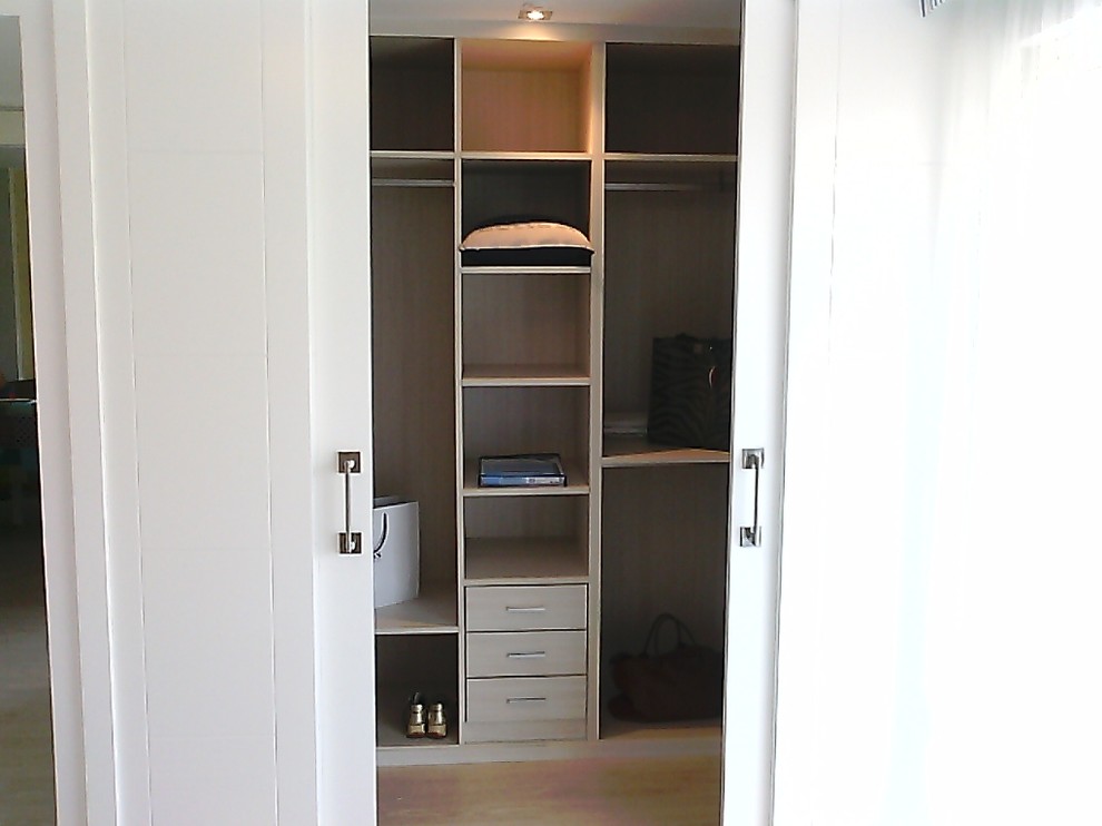 На фото: гардеробная комната среднего размера, унисекс в средиземноморском стиле с открытыми фасадами, светлыми деревянными фасадами и светлым паркетным полом