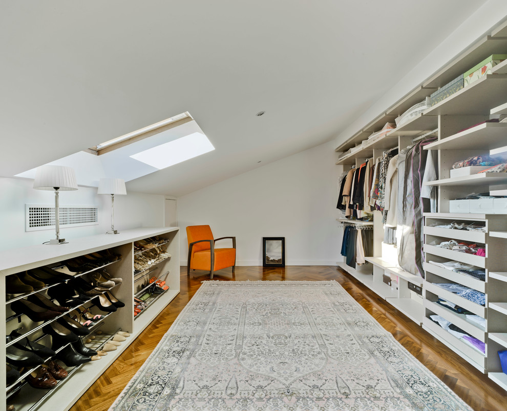 Großes Modernes Ankleidezimmer mit Ankleidebereich, offenen Schränken, weißen Schränken und braunem Holzboden in Madrid