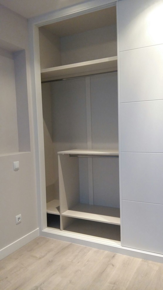 Foto di un piccolo armadio o armadio a muro unisex minimalista con ante lisce, ante grigie e parquet chiaro