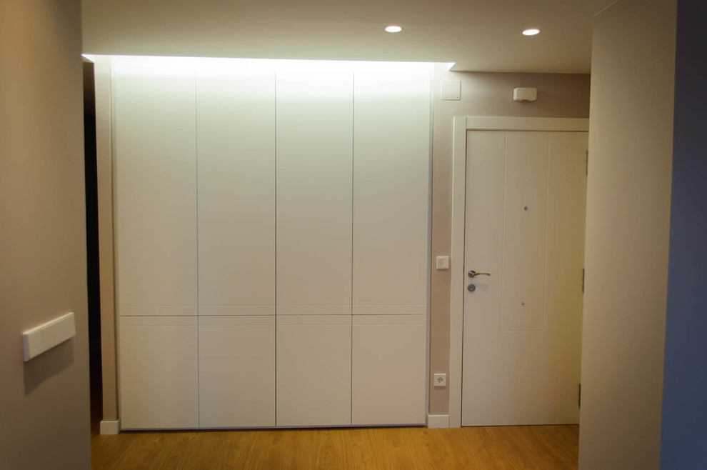 Mittelgroßes, Neutrales Modernes Ankleidezimmer mit braunem Holzboden, flächenbündigen Schrankfronten und weißen Schränken in Sonstige
