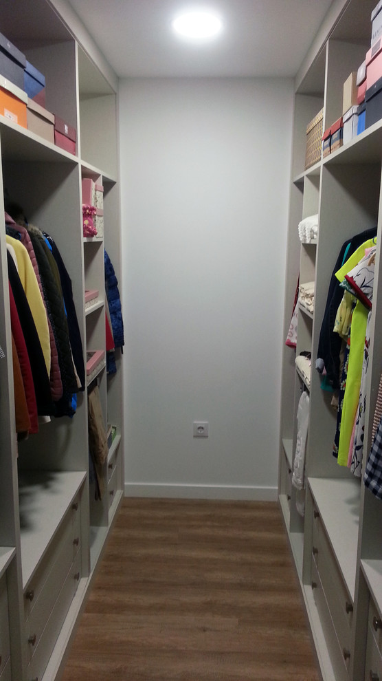 Modelo de armario vestidor unisex clásico renovado de tamaño medio con armarios abiertos, puertas de armario blancas y suelo de madera en tonos medios