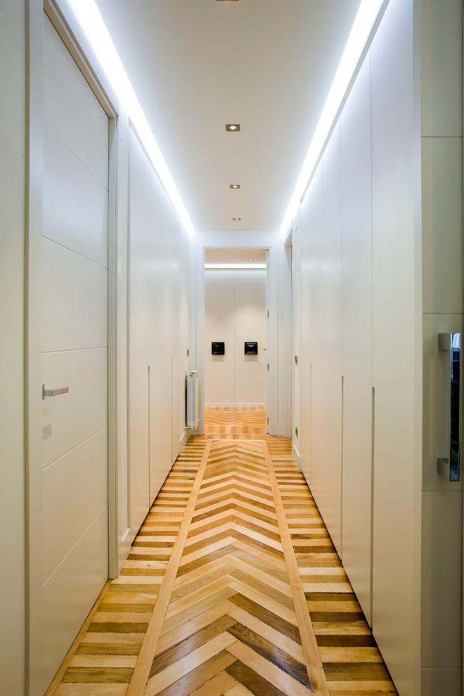 Idée de décoration pour un grand dressing room tradition avec un placard avec porte à panneau encastré, des portes de placard blanches et un sol en bois brun.