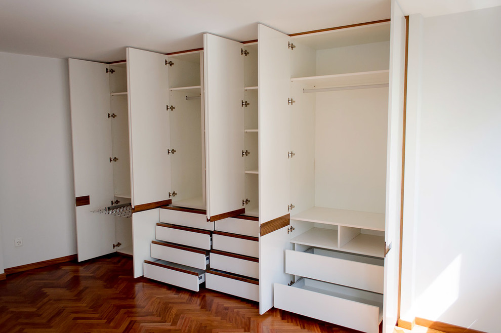 Design ideas for a medium sized traditional gender neutral standard wardrobe in Other with flat-panel cabinets, white cabinets and dark hardwood flooring.