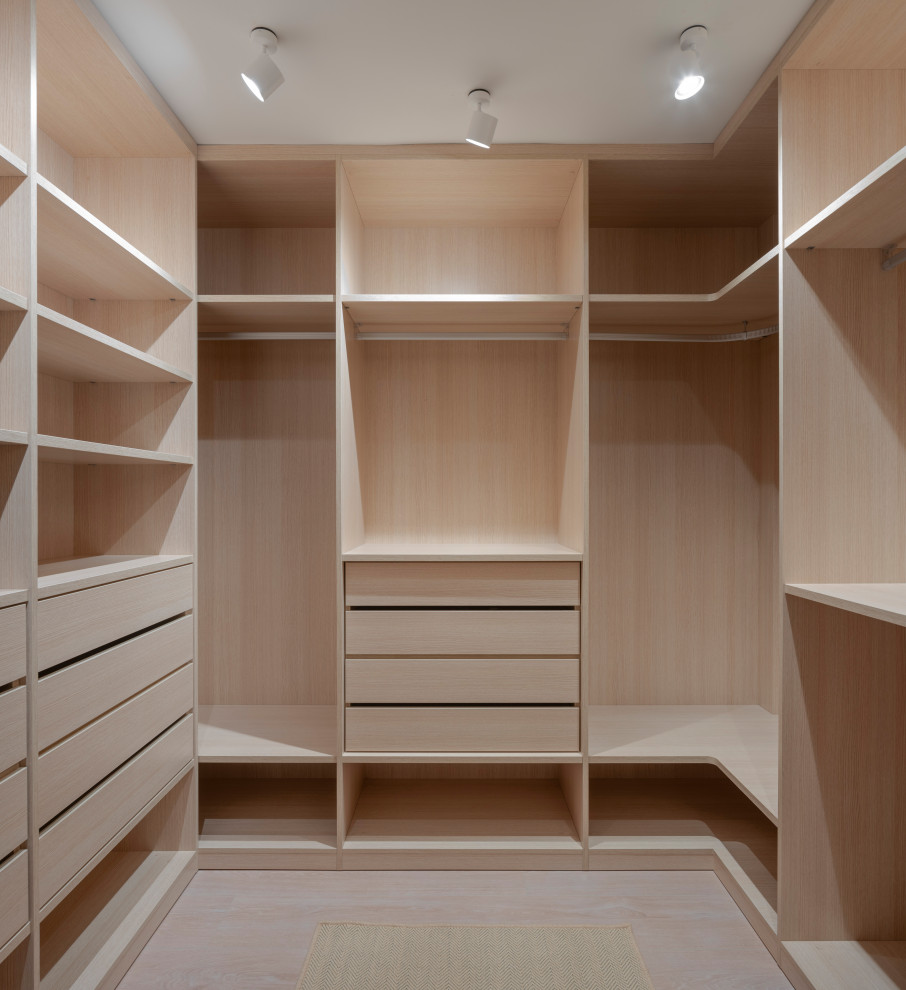 Aménagement d'un grand dressing room classique en bois clair neutre avec un placard sans porte, sol en stratifié et un sol marron.