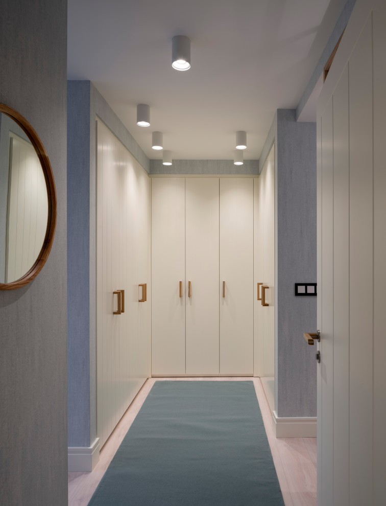 На фото: большая гардеробная комната унисекс в скандинавском стиле с плоскими фасадами, белыми фасадами, полом из ламината и синим полом с