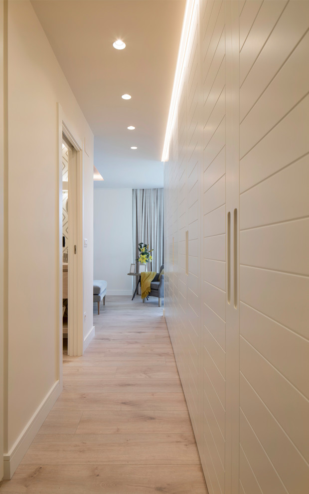 Источник вдохновения для домашнего уюта: гардеробная комната среднего размера, унисекс в стиле неоклассика (современная классика) с белыми фасадами, полом из ламината, бежевым полом и плоскими фасадами