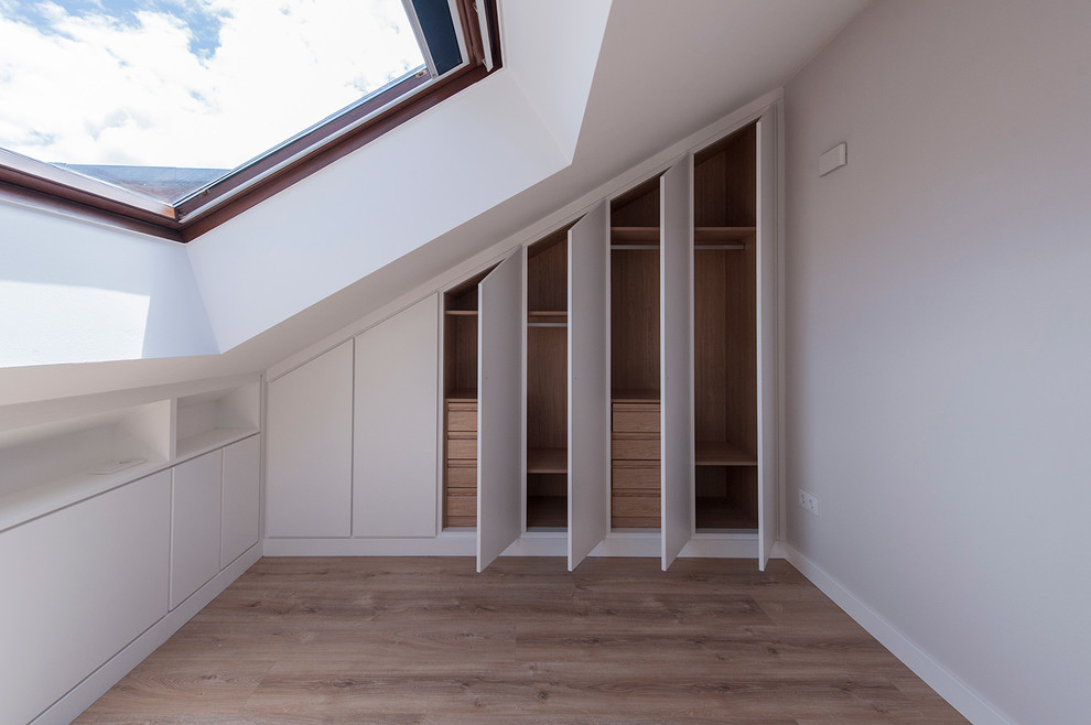 Example of a mid-sized danish gender-neutral walk-in closet design in Other with flat-panel cabinets and white cabinets