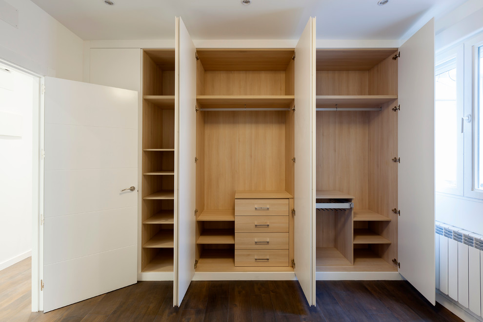 Diseño de armario y vestidor moderno de tamaño medio con suelo de madera oscura