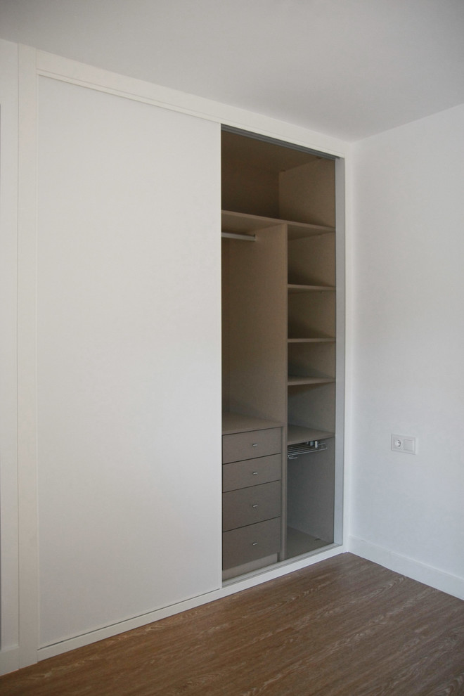 Imagen de armario unisex contemporáneo de tamaño medio con armarios con paneles lisos, puertas de armario blancas y suelo de madera en tonos medios
