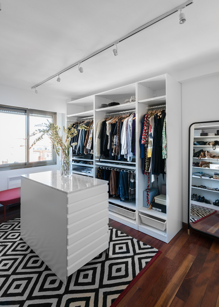 Diseño de armario vestidor unisex contemporáneo de tamaño medio con armarios abiertos, puertas de armario blancas y suelo de madera oscura