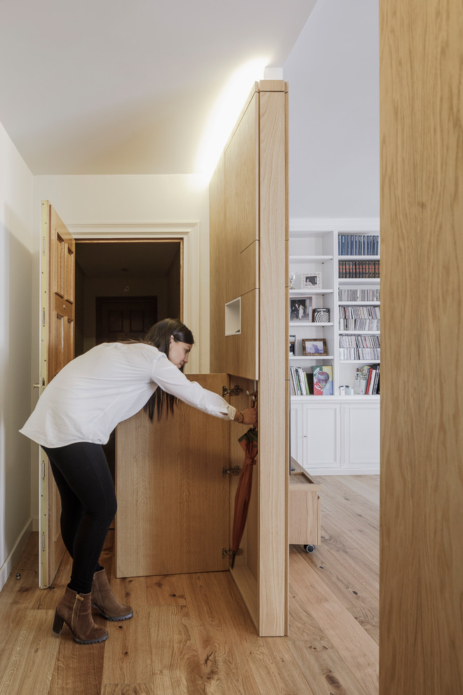 Moderner Begehbarer Kleiderschrank mit hellbraunen Holzschränken und braunem Holzboden in Madrid