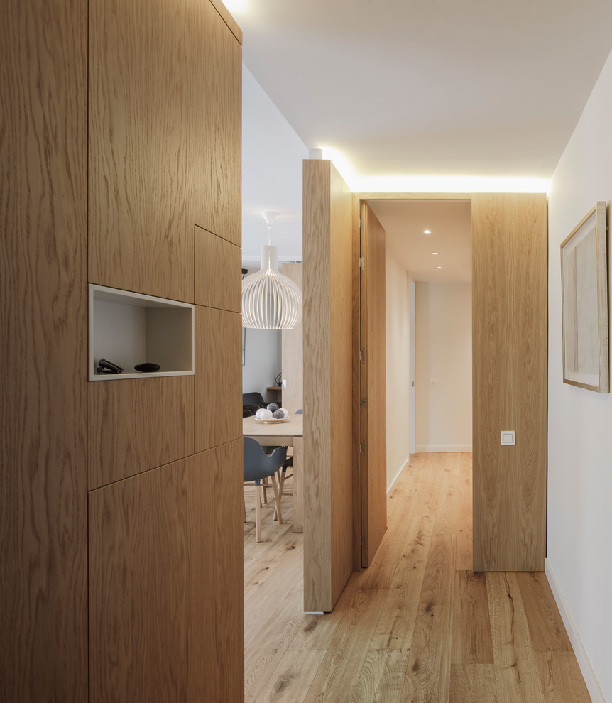 This is an example of a modern walk-in wardrobe in Madrid with medium wood cabinets and medium hardwood flooring.