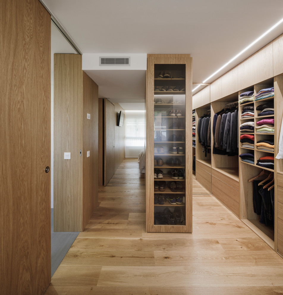 Moderner Begehbarer Kleiderschrank mit hellbraunen Holzschränken, braunem Holzboden, flächenbündigen Schrankfronten und beigem Boden in Madrid