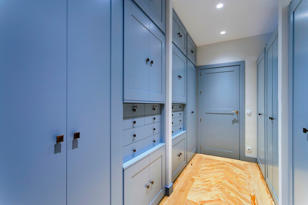Ejemplo de armario unisex actual grande con armarios con paneles empotrados, puertas de armario azules y suelo de madera clara