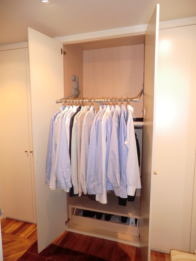 Imagen de armario unisex clásico renovado pequeño con armarios con paneles lisos, puertas de armario blancas y suelo de madera en tonos medios