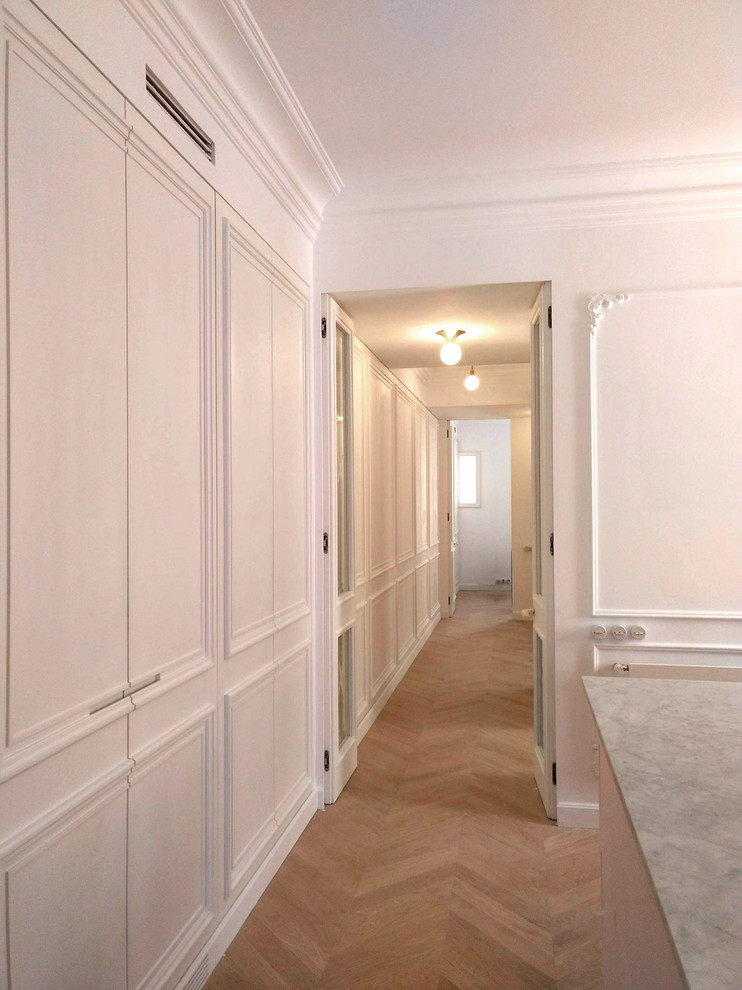 マドリードにあるラグジュアリーな広いトランジショナルスタイルのおしゃれなウォークインクローゼット (インセット扉のキャビネット、白いキャビネット、無垢フローリング、茶色い床) の写真
