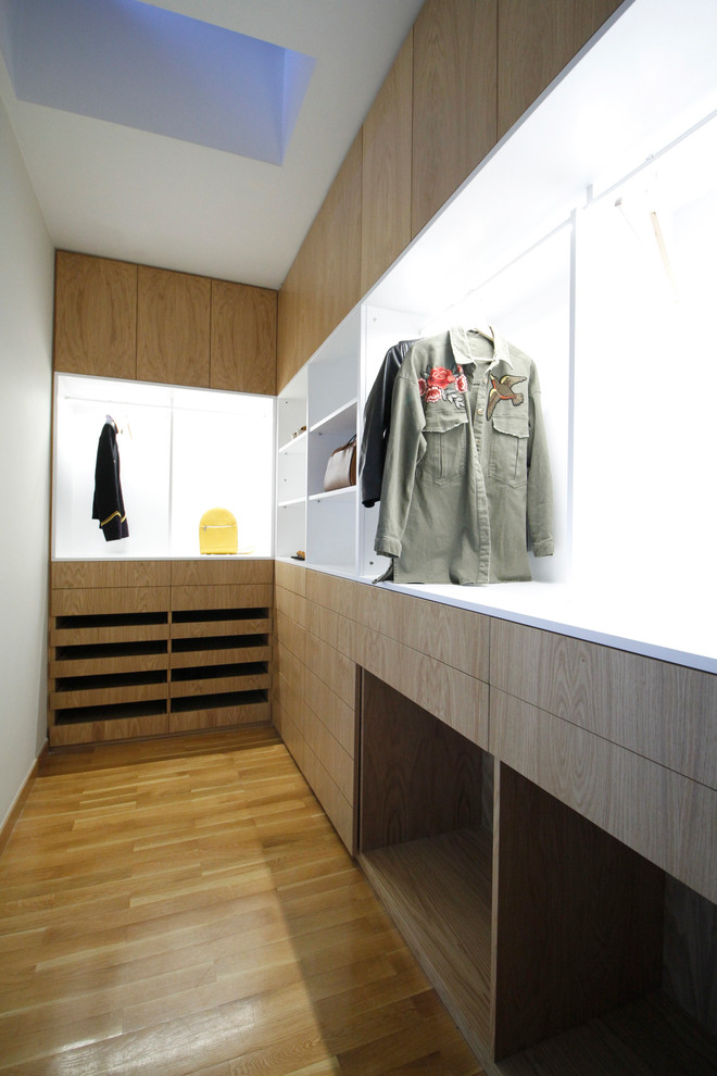 Ejemplo de armario vestidor contemporáneo de tamaño medio con armarios con paneles lisos, puertas de armario de madera clara y suelo de madera clara