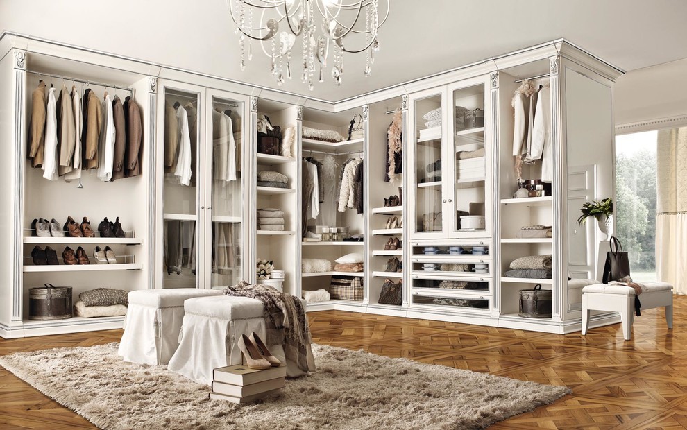 На фото: большая гардеробная комната унисекс в классическом стиле с стеклянными фасадами, белыми фасадами и паркетным полом среднего тона