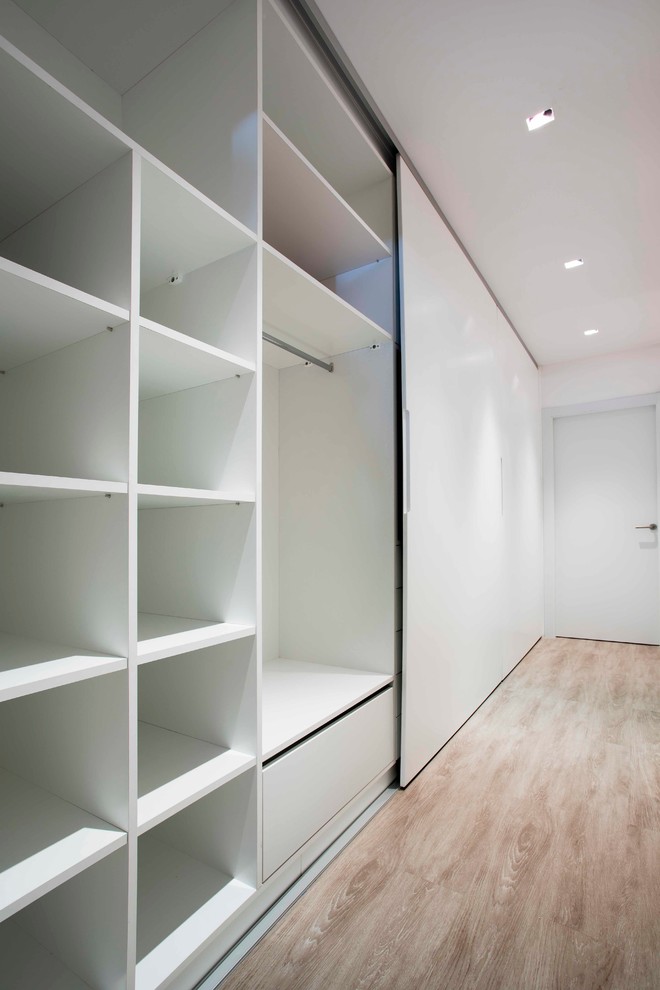 Imagen de armario unisex contemporáneo grande con armarios con paneles lisos, puertas de armario blancas y suelo de madera clara
