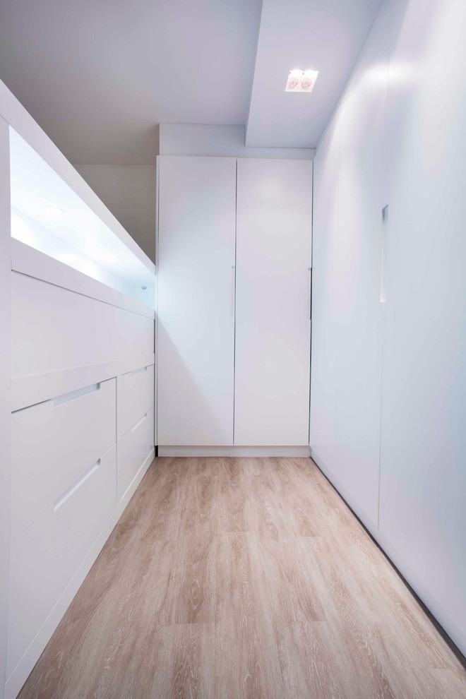 Ejemplo de armario unisex contemporáneo grande con armarios con paneles lisos, puertas de armario blancas y suelo de madera clara