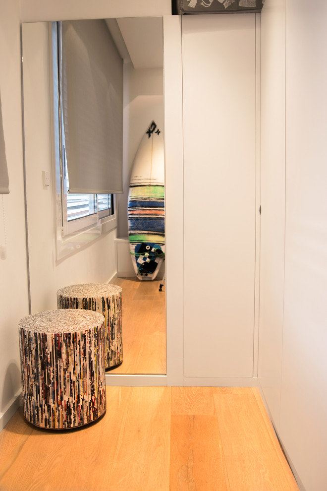 Idéer för små funkis walk-in-closets för könsneutrala, med släta luckor, vita skåp och mellanmörkt trägolv