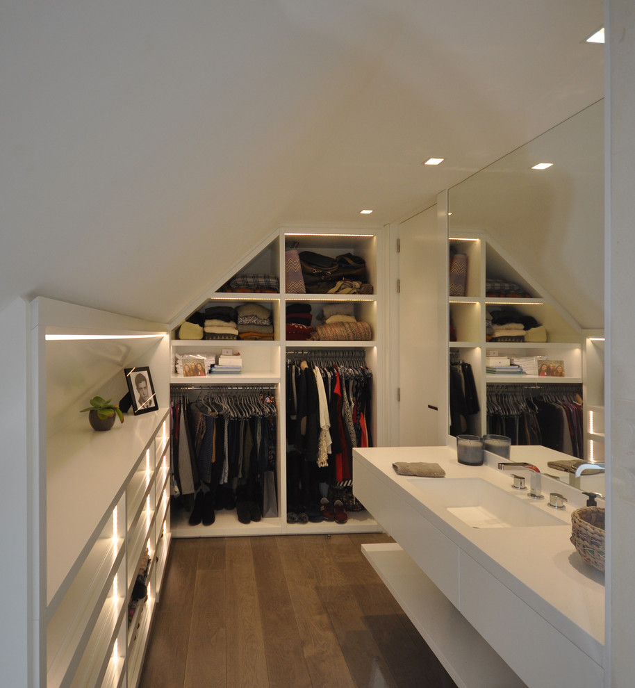 Medium sized contemporary gender neutral walk-in wardrobe in Madrid with flat-panel cabinets, white cabinets and dark hardwood flooring.