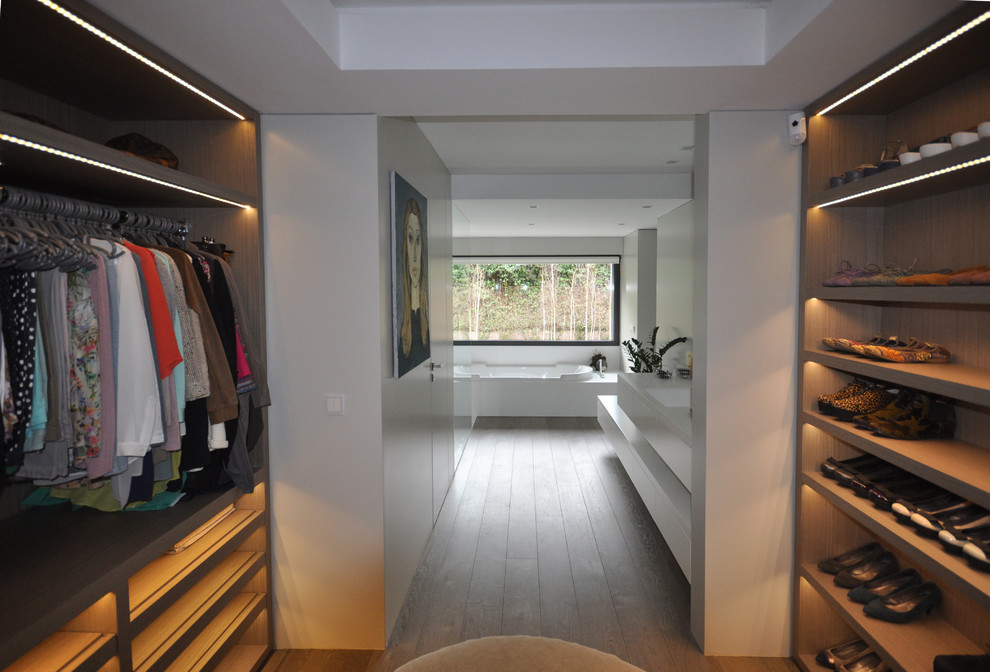 Diseño de armario vestidor unisex actual grande con armarios abiertos, puertas de armario de madera oscura y suelo de madera en tonos medios