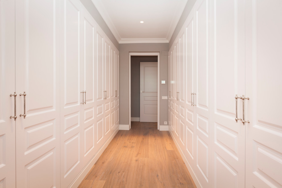 Inspiration for a large traditional gender neutral standard wardrobe in Barcelona with recessed-panel cabinets, white cabinets and medium hardwood flooring.