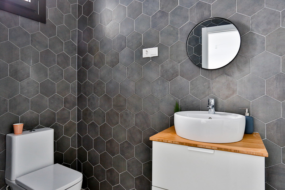 Imagen de aseo minimalista con sanitario de dos piezas, paredes grises, lavabo sobreencimera y encimera de madera
