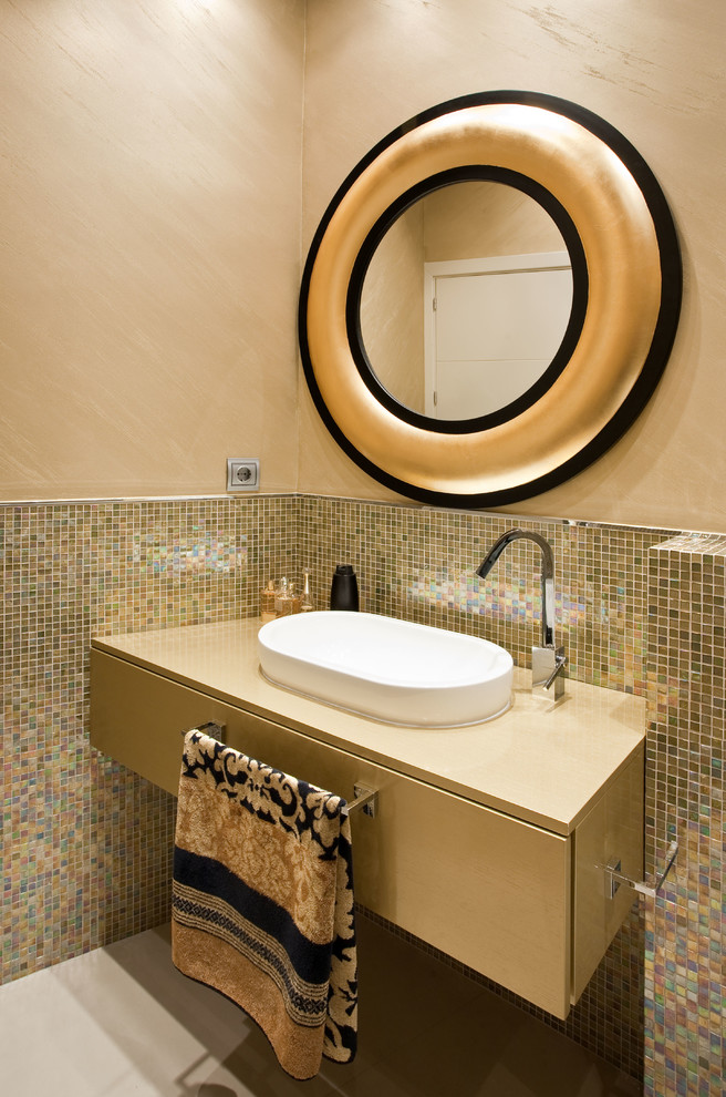 Moderne Gästetoilette mit flächenbündigen Schrankfronten, beigen Schränken, farbigen Fliesen, Mosaikfliesen, beiger Wandfarbe, Aufsatzwaschbecken, grauem Boden und beiger Waschtischplatte in Sevilla