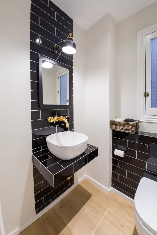Exemple d'un petit WC suspendu tendance avec des carreaux de céramique, un mur blanc, un plan de toilette en bois, un carrelage noir, un sol en bois brun, un lavabo suspendu et un plan de toilette noir.