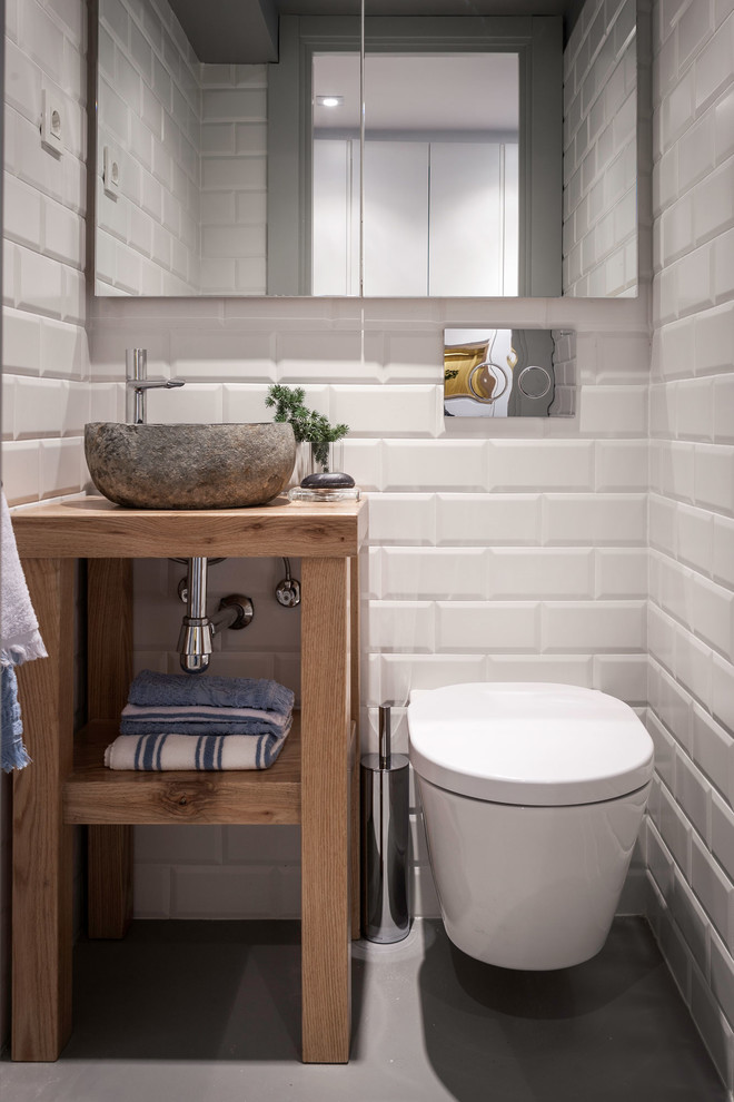 Cette photo montre un petit WC suspendu tendance en bois clair avec un carrelage blanc, des carreaux de céramique, un mur blanc, sol en béton ciré, un lavabo de ferme, un plan de toilette en bois et un plan de toilette marron.
