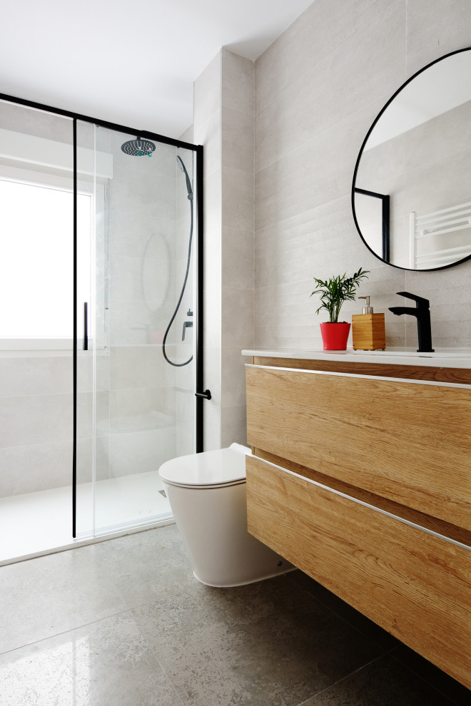 Skandinavisk inredning av ett litet badrum, med släta luckor, vita skåp, vit kakel, keramikplattor, klinkergolv i porslin och grått golv