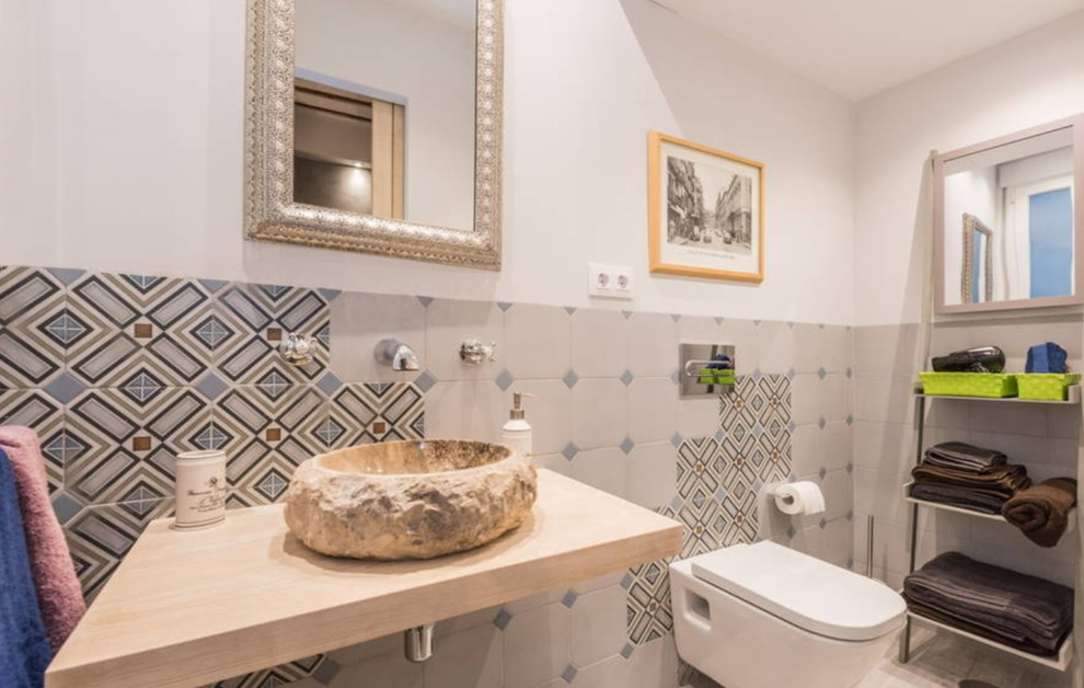 Aménagement d'un WC suspendu montagne de taille moyenne avec un mur multicolore, une vasque et un plan de toilette en bois.