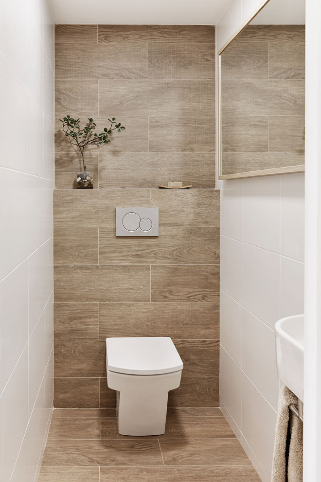 Inspiration för ett litet nordiskt toalett, med vita skåp, en vägghängd toalettstol, vit kakel, keramikplattor, vita väggar, klinkergolv i porslin, ett väggmonterat handfat och brunt golv