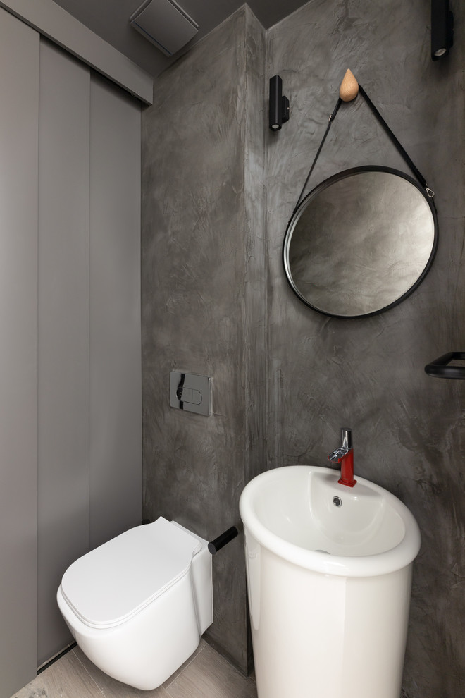 Diseño de aseo contemporáneo pequeño con sanitario de pared, paredes grises, suelo de baldosas de porcelana, lavabo con pedestal y suelo gris
